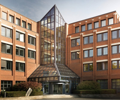 A modern brick and glass office building with a central triangular glass atrium and entrance