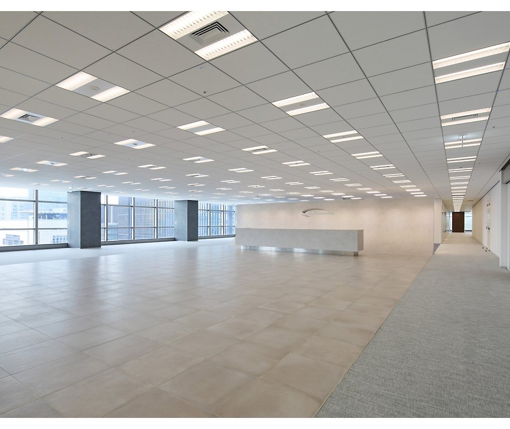 Modernt, tomt kontorsutrymme med plattgolv, vita väggar och stora fönster som släpper in naturligt ljus