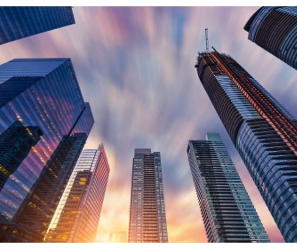 Stadsgezicht van moderne wolkenkrabbers onder een kleurrijke lucht met dynamische wolkbewegingen tijdens zonsondergang.
