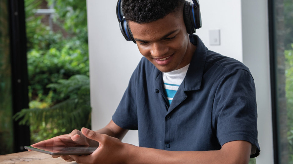 A young person listening to audio from mobile device over headphones.