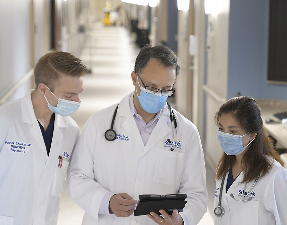 Eine Gruppe von Ärzten mit Gesichtsmasken, die ein Smartphone beobachten