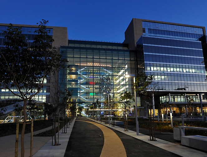 A large glass building with a sidewalk in front of it.