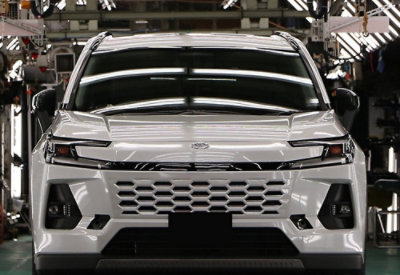 Front view of a white SUV on an automotive production line inside a factory.