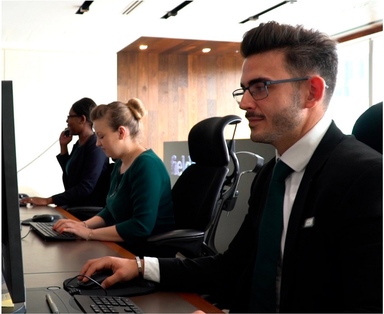 Um grupo de pessoas a trabalhar em computadores num escritório.