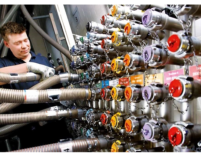 Um homem está a trabalhar numa máquina com várias mangueiras de cores diferentes.
