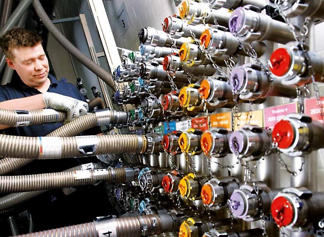 Um homem está a trabalhar numa máquina com várias mangueiras de cores diferentes.