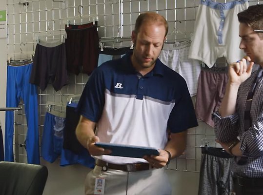 Two people in a clothing store looking at a tablet.