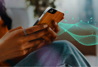 Person using smartphone with glowing digital graphics emanating from screen, highlighting modern technology use.