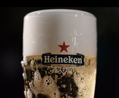 A close-up of a Heineken beer glass filled with foamy, chilled beer.