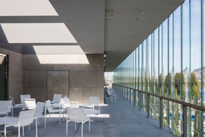 An office café with tables and chairs next to a wall of windows
