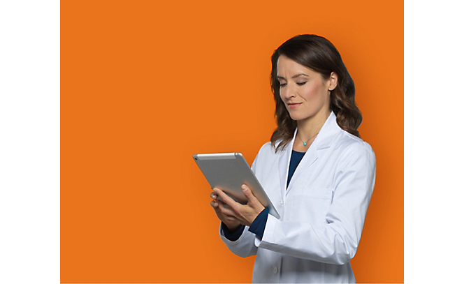 A person in a white coat holding a tablet