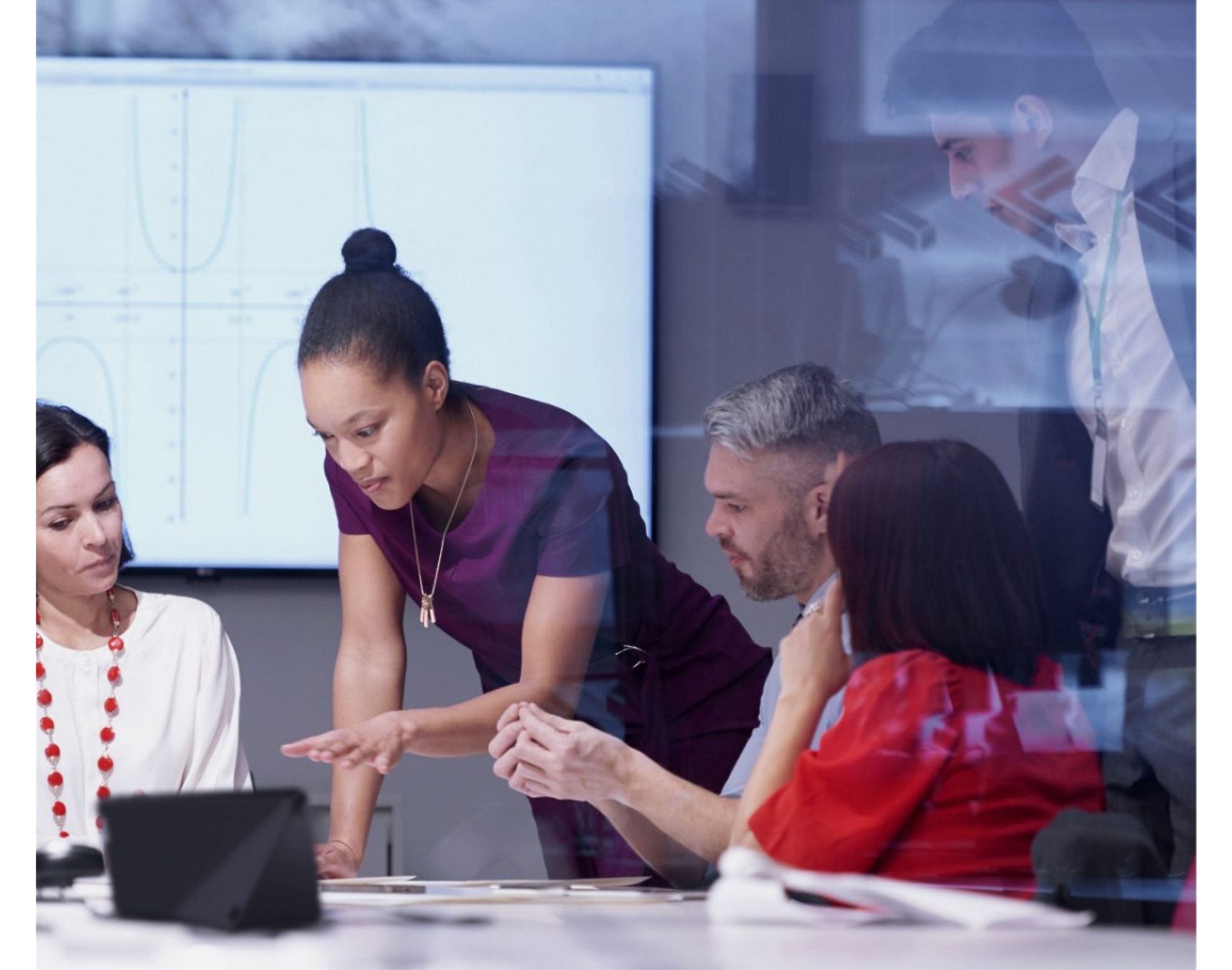 Un gruppo eterogeneo di professionisti che discutono intorno a un portatile in un ufficio moderno.