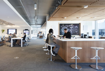A modern office features an open layout with people working at tables in the background 
