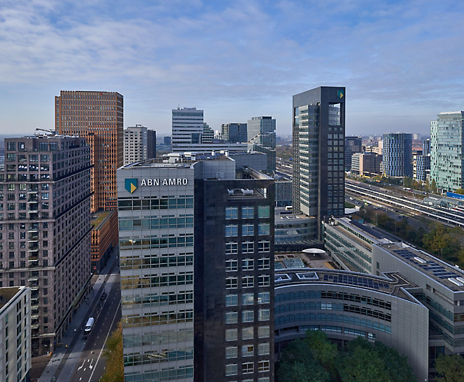 Utsikt fra høyden over et moderne urbant forretningsområde med høyhus og en klar himmel.