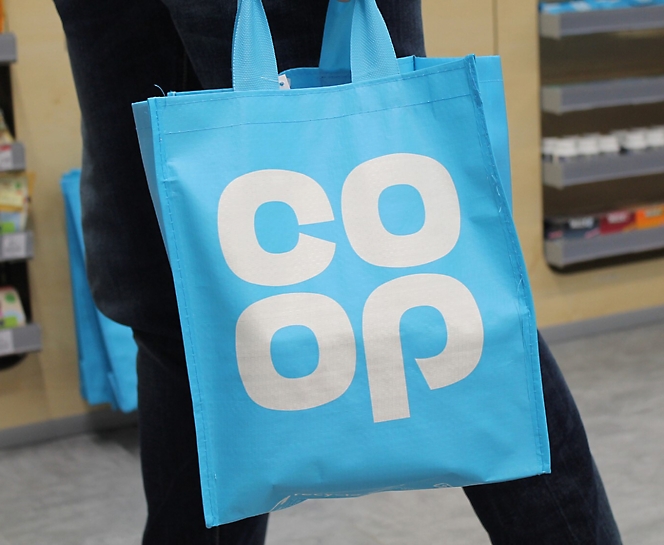 A person holding a blue bag and co-op written on it.