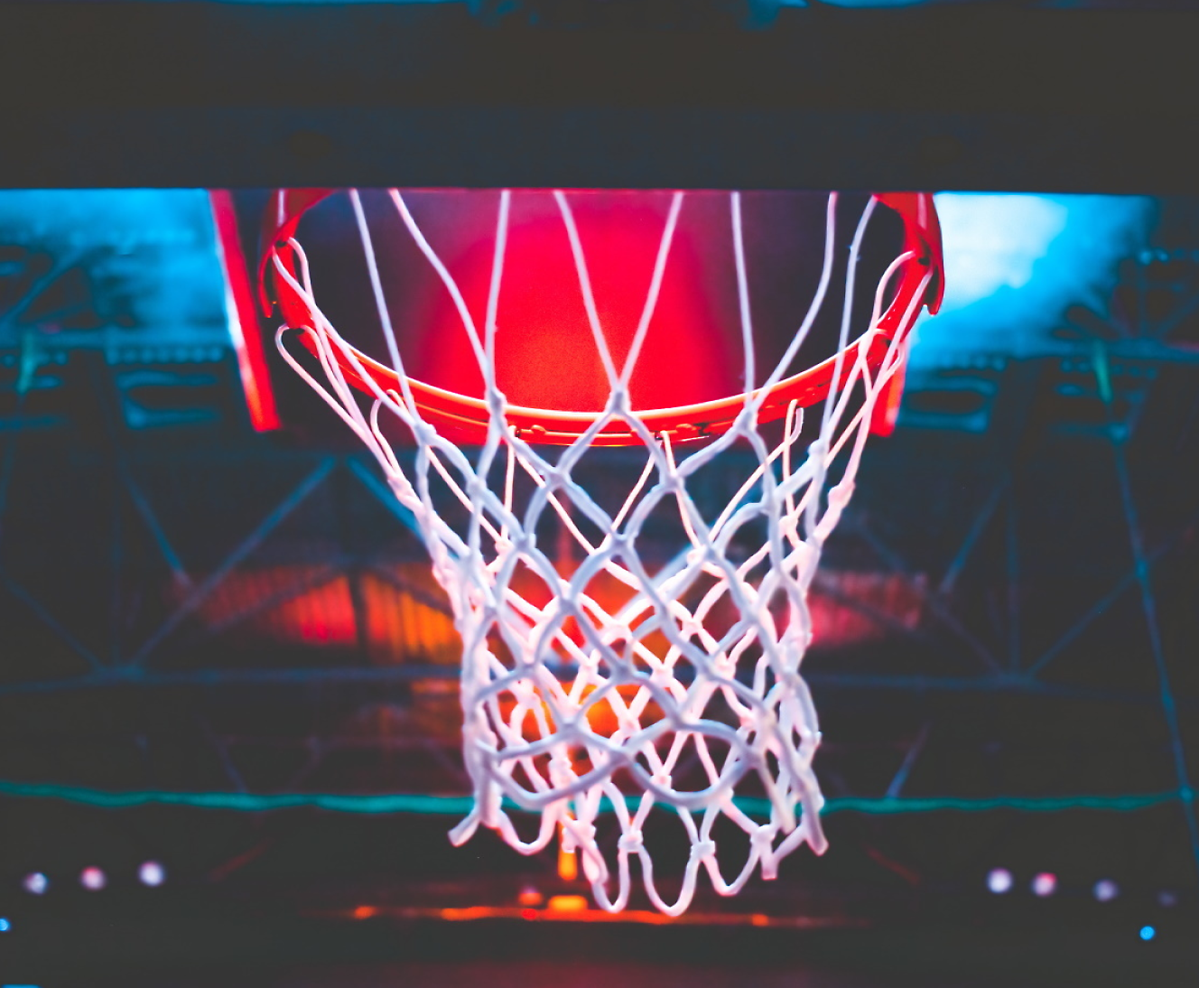 Basketball hoop illuminated by red light from below with a blurred background.