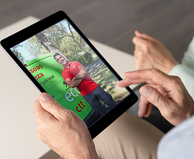 Orang menggunakan tablet yang menampilkan gambar seorang pria berdiri di luar ruangan pada layar.