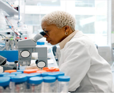 A woman in a medical facility using microscope