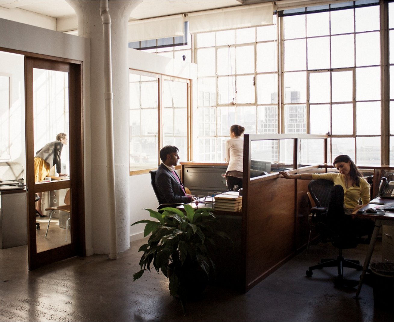 En gruppe personer, der sidder ved skriveborde på et kontor.