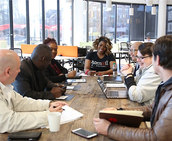 En grupp personer som sitter på ett kontor runt ett bord och diskuterar