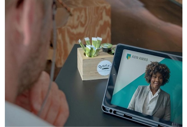 Uomo in primo piano durante una videochiamata con una donna sullo schermo di un tablet.