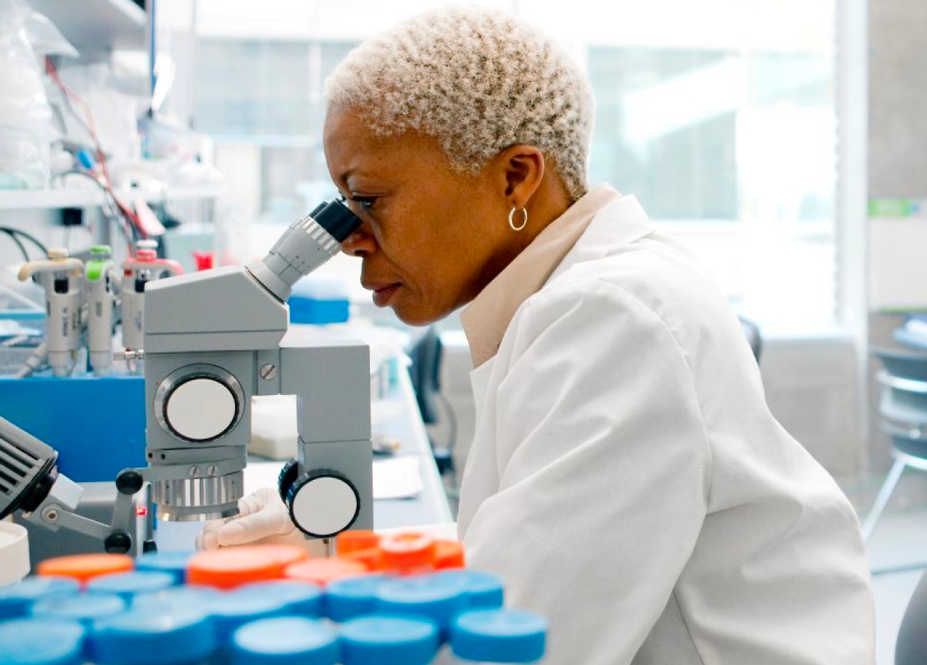 A woman in a medical facility using microscope