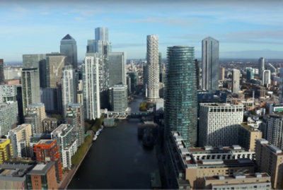 Aerial view of a modern cityscape with high-rise buildings, a river, and scattered clouds.