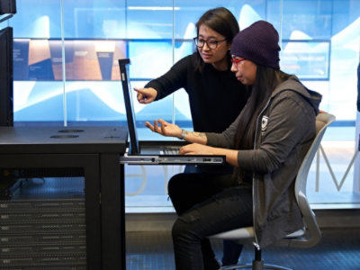 A woman pointing at a laptop.