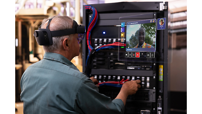 En tekniker med vr-headset arbejder på en kompleks række kabler i et industrielt miljø med en synlig digital grænseflade