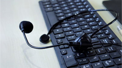 Black headset with a microphone resting on a black computer keyboard.