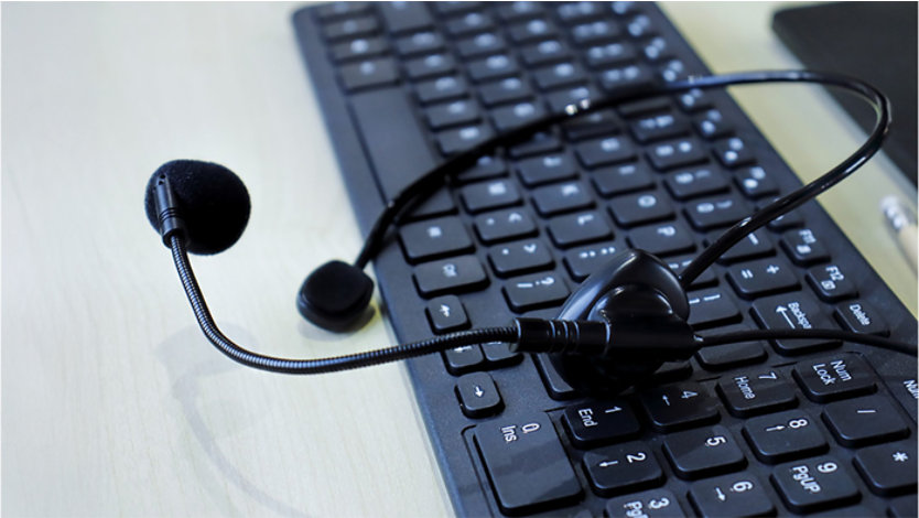 Black headset with a microphone resting on a black computer keyboard.