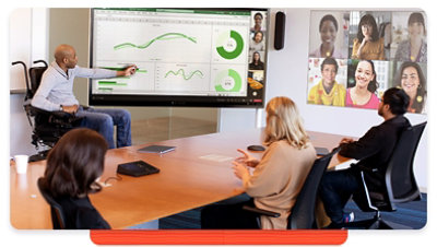 Man using a wheelchair leads a presentation to colleagues in a conference room and in a video call 