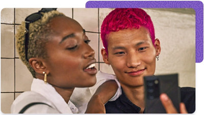 Two colleagues, smiling, looking at a phone screen