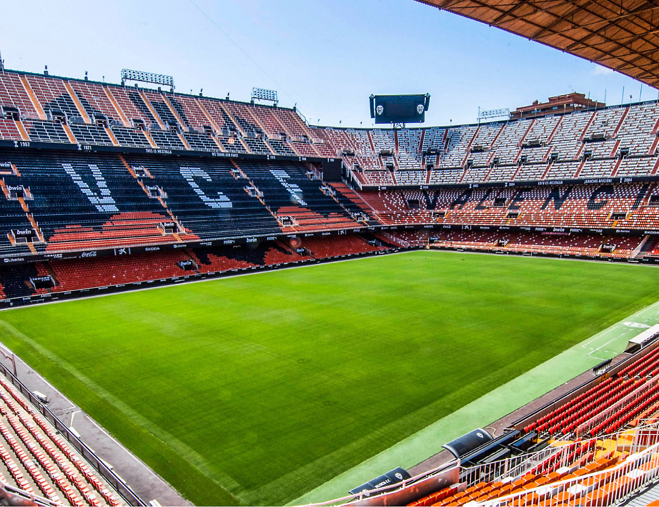 Vnitřek fotbalového stadionu s oranžovým hřištěm.