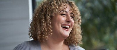 微笑んでいる巻き髪の女性。