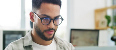 A man in glasses is looking at his phone.