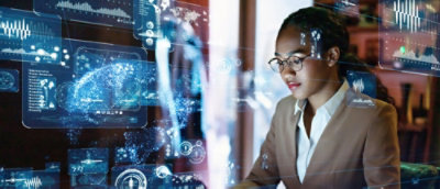 A professional woman analyzing advanced digital data and graphs on a futuristic holographic display screen at night.