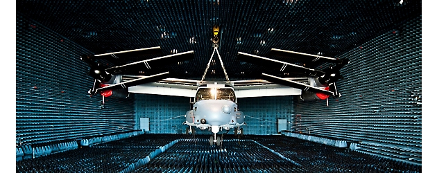Un elicopter în curs de testare într-o cameră izolată fonic, tapetată cu piramide fonoabsorbante de burete albastru.