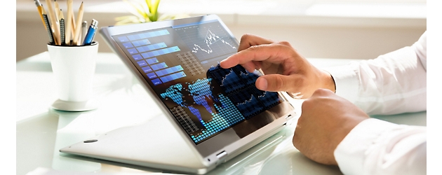Людина аналізує фінансові дані на екрані планшета з інтерактивними діаграмами та графіками в офісі з яскравим оформленням.
