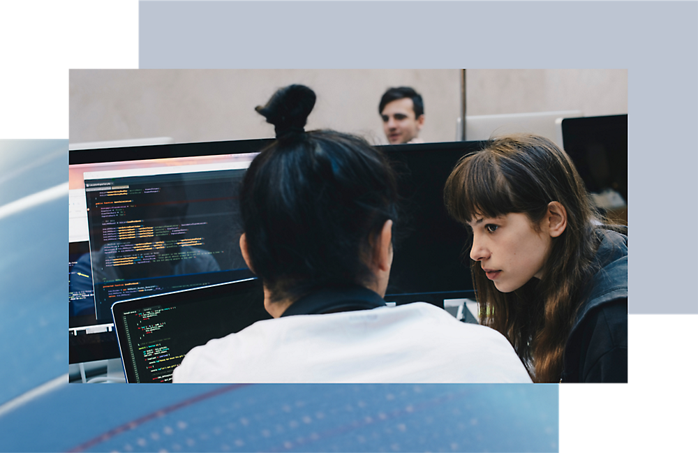 Dos personas analizando código en una pantalla de equipo en una configuración moderna de la oficina.