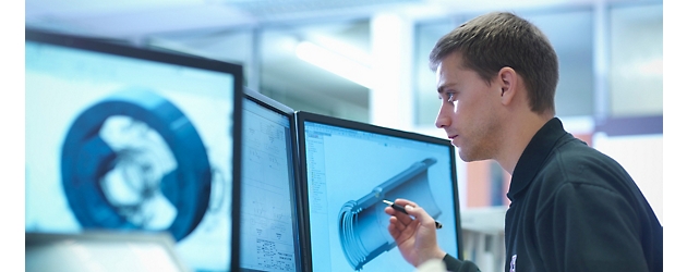 Homme analysant un modèle 3D sur des écrans d’ordinateur dans un environnement de bureau technique ou d’ingénierie.