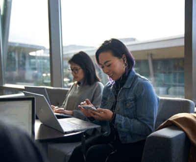 A person sitting in a chair looking at her phone and smiling