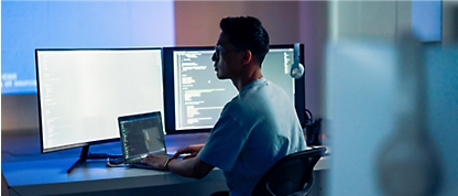 En person som sitter ved et skrivebord og arbeider på en bærbar datamaskin