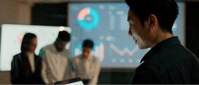 Man presenting data on a screen to a group of colleagues in a modern office setting.