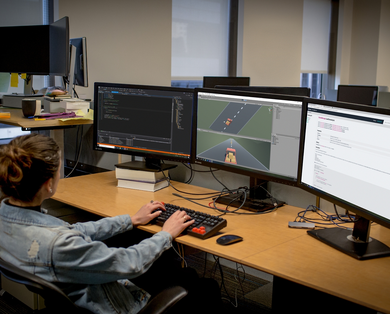 Una sviluppatrice di software che lavora con una postazione con più monitor in un ufficio e scrive codice ed esegue il debug di software.