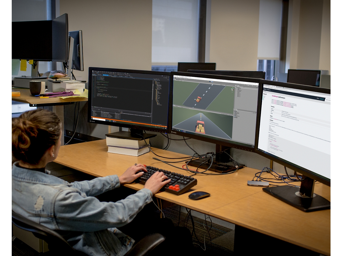 Eine Softwareentwicklerin arbeitet in einem Büro an einem Setup mit mehreren Bildschirmen und programmiert und debuggt Software.