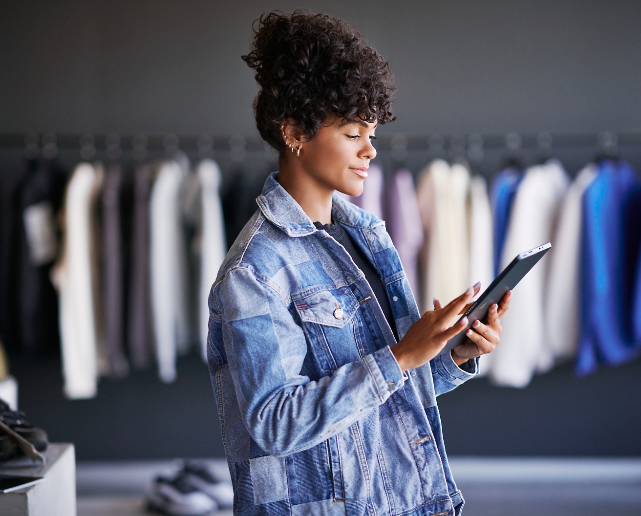 Une femme vêtue d’une veste en jean utilise une tablette dans un magasin de vêtements
