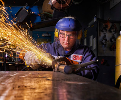 En man med hjälm och skyddsväst som använder skärbrännare