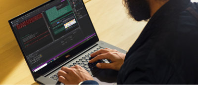 コーディング ソフトウェアが開かれており、コード行とさまざまなプログラミング ツールが表示されている Dell のノート PC に入力している人物 