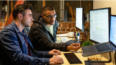 Two male developers working and collaborating in a casual office at night.